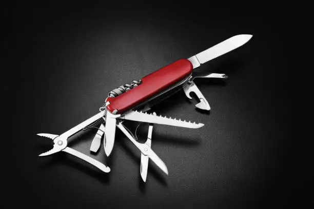 Many task swiss army knife on black background. Multi-tool