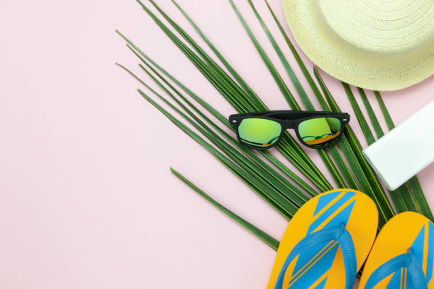 Table top view aerial image of items to travel summer holiday background concept.Flat lay essentials accessories for travel to beach trip.Fashion sun glasses with slipper & hat on green coconut leaf. imagen aérea de la vista superior de tabla de artículos de viaje en concepto de fondo de vacaciones de verano. accesorios esenciales endecha plana para viajar a viaje de playa. gafas de sol de moda con zapatillas y sombrero de hoja de coco verde.