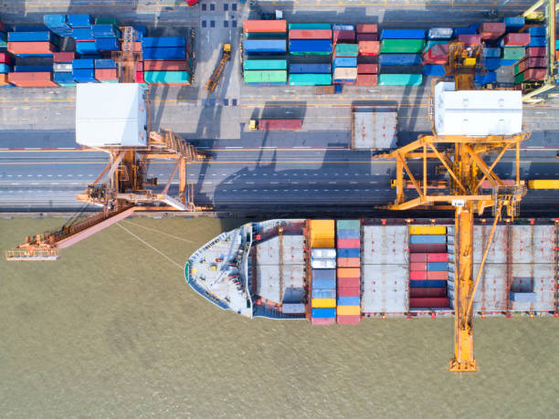 istock Container ship in export and import business and logistics. Shipping cargo to harbor by crane. Water transport International. Aerial view and top view 956101594