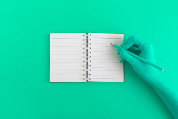 istock Flat lay of female hand with notepad on green background 956117976