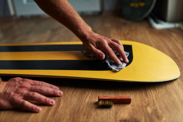 man rubs snowboard sponge wax on  wooden floor stock photo