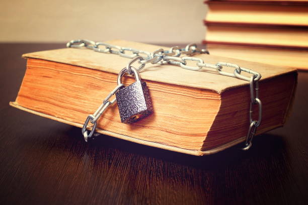 istock old book wrapped with chain and locked on padlock on table, concept, toned 956118468