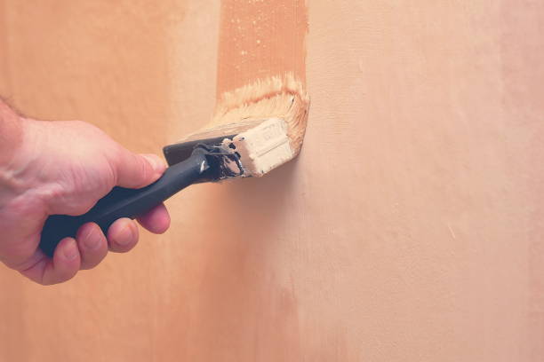 istock hand holding paintbrush and repainting wall, toned, copy space 956118490