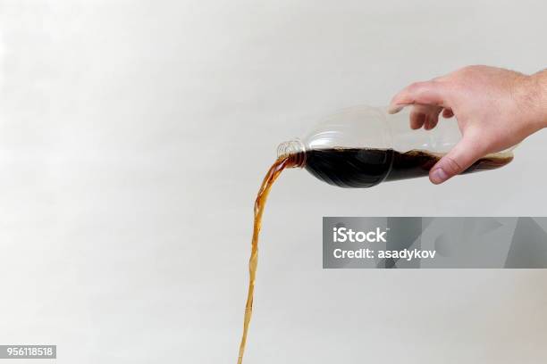 Hand Pouring Out Cola From Plastic Bottle On Gray Background Copy Space Stock Photo - Download Image Now