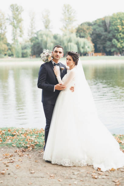 istock Newly married couple running and jumping in park while holding hands 956119762