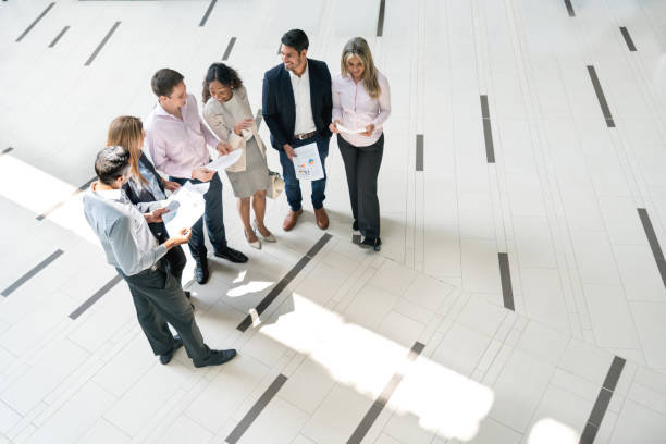 istock Diverse young business group discussing something on the lobby while holding documents looking very happy 956119768