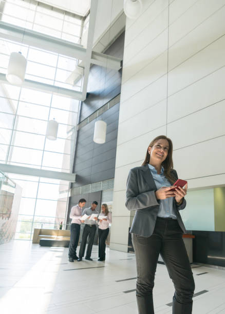 istock Thoughtful business woman looking up while holding her smartphone smiling 956119784
