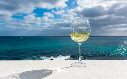 One glass of cold white wine served on outdoor terrace with beautiful romantic  sea view