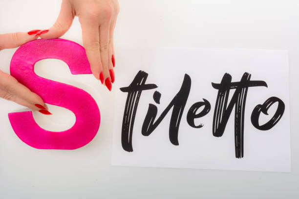 Stiletto begins with red cardboard letter S  Mature woman with red stiletto manicure places the red cardboard begin letter