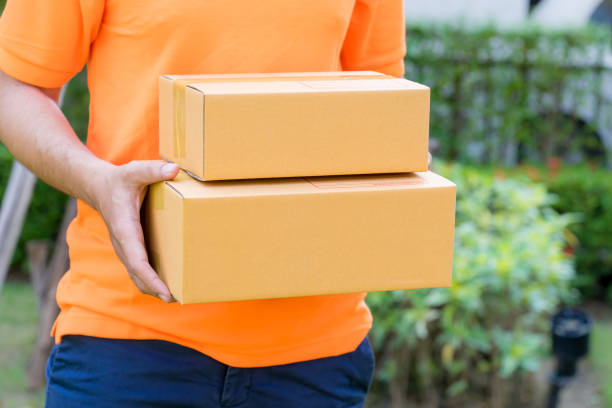 istock Delivery man in orange is handing packages 956127760