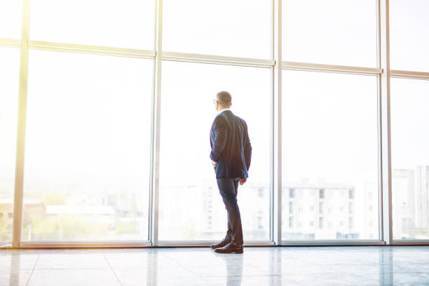 istock Senior businessman looking out panoramic window in office 956130182