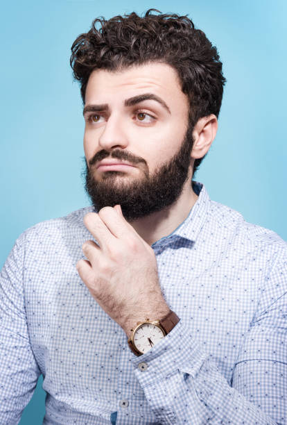istock Partret brooding young men. Dark hair, beard and mustache. Light shirt and wrist watch 956130406