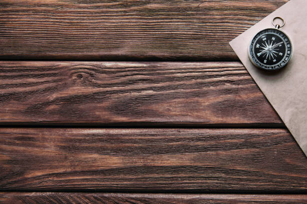 istock Compass and paper on wooden table. 956131008