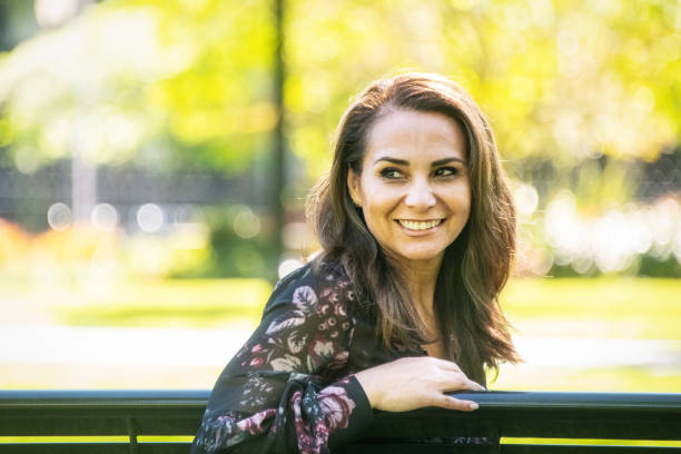 istock Smiling woman sitting in a bench looking away 956136794