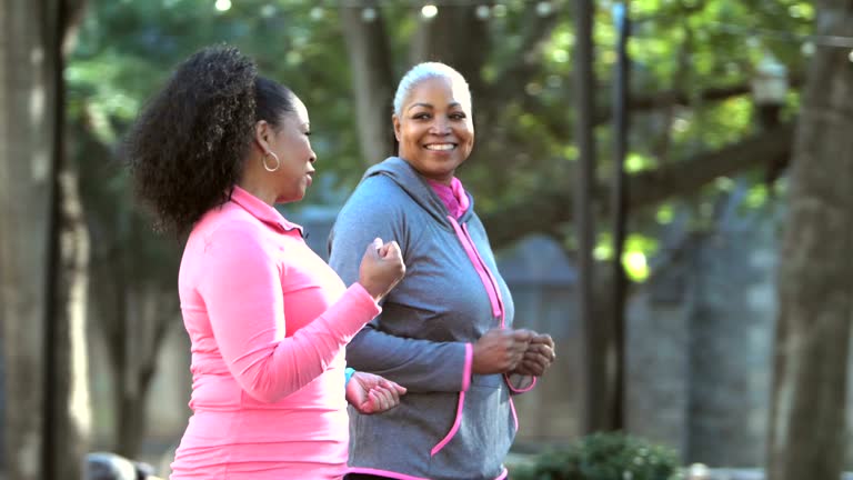 Two women power walking in the city, talking and smiling