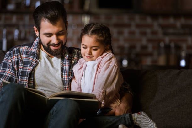istock happy father with daughter hugging on couch and reading book at home 956147948