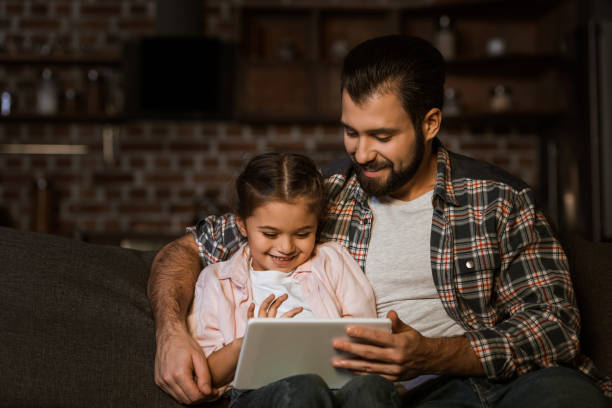 istock happy father with daughter sitting on couch and using tablet 956148276
