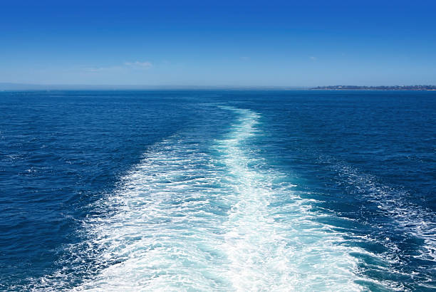 Boat wake in the sea, on a brilliant sunny day.  This is the view behind a car ferry.