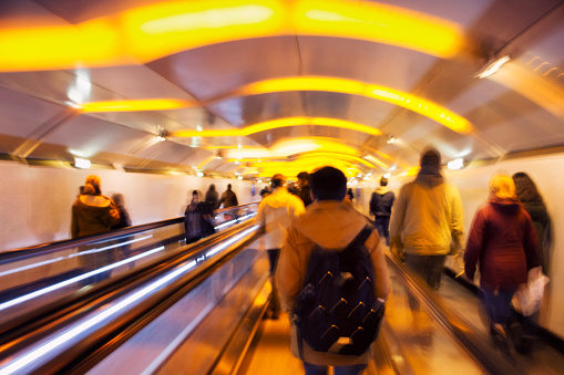 Blurry motion image of people walking horizontal escalators in subway station in Paris.