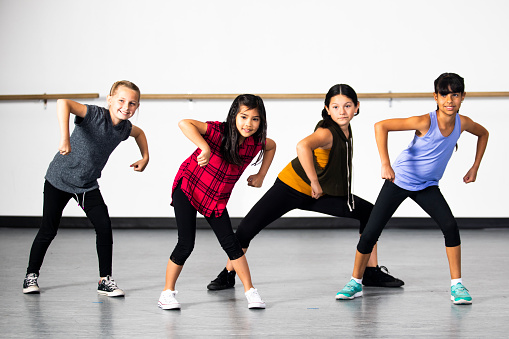 A diverse group of young girls practicing hip hop dance at a dance studio