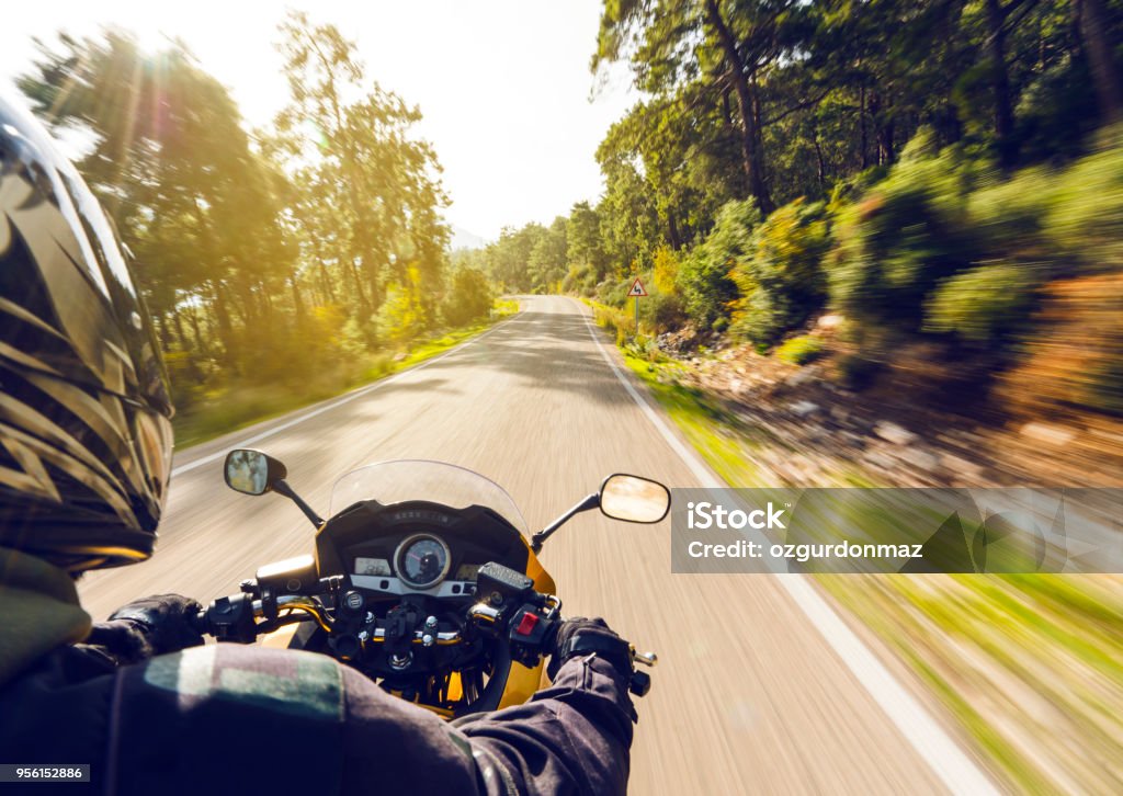 Motorbike Ride On A Country Road Motorcycle speeding down on an empty country road from over rider"u2019s point of view. Focus is on the motorbike with road motion blurred Motorcycle Stock Photo