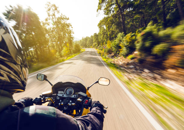Motorbike Ride On A Country Road Motorcycle speeding down on an empty country road from over rider"u2019s point of view. Focus is on the motorbike with road motion blurred motorcycle photos stock pictures, royalty-free photos & images