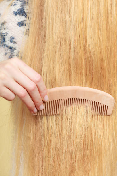 istock Blonde woman brushing her hair with comb 956157720