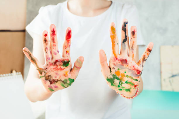 istock Closeup of woman's hands painted with watercolors, selective shallow focus 956160320