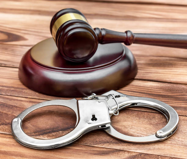 istock Handcuffs and judge's gavel with stand on wooden table. 956160424