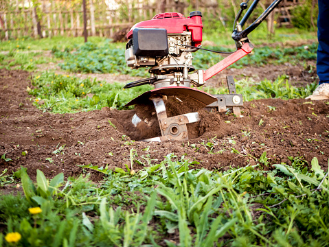 close up rotating cultivating tiller in the garden