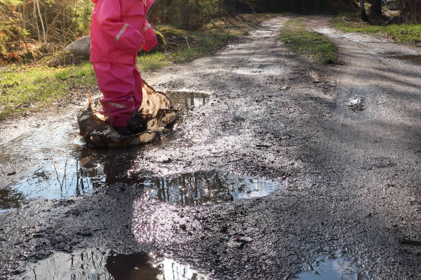 istock Girl jumping in a muddy water pool / puddle 956161866