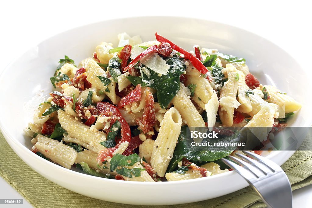 Close up of delicious pasta on white plate Pasta salad with spinach leaves, bell peppers, sundried tomatoes, and parmesan cheese.  Healthy fresh eating.  Please see also: Pasta Salad Stock Photo