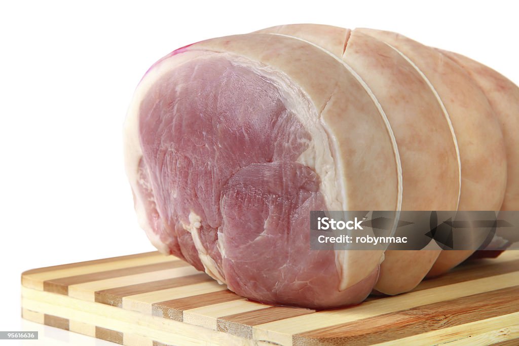 A tied up piece of pork on a striped chopping board Loin of pork, trussed and ready for roasting.  Please see more fresh meat, ready for cooking: Loin Stock Photo