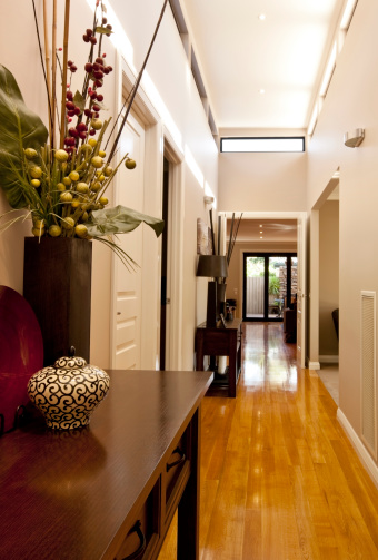 Entrance hall of new showcase home, with polished floorboards, downlighting, and elegant decor.