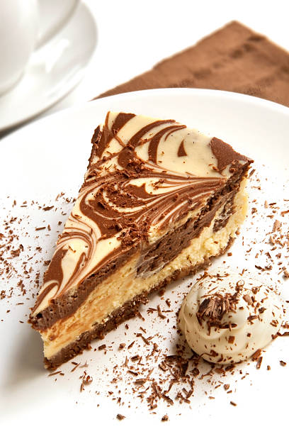 Chocolate marble cheesecake with cream and shaved chocolate, and a cup of coffee.  Please see also:   http://robynm.smugmug.com/photos/269756322_QZdYd-L.jpg