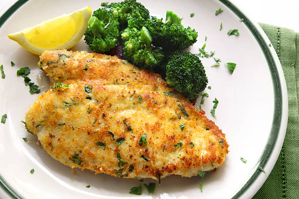 Chicken breast plated with broccoli florets and lemon wedge