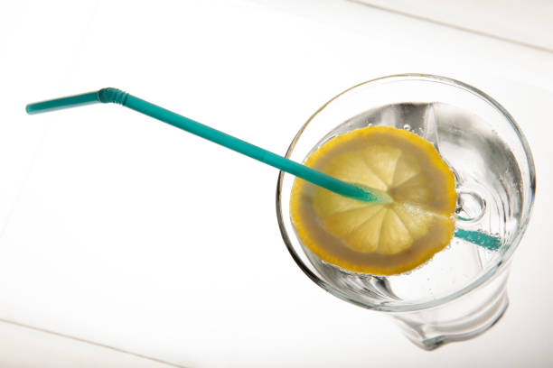 A  glass of fresh drinking water and a lime. mineral water , lime and straw on white background