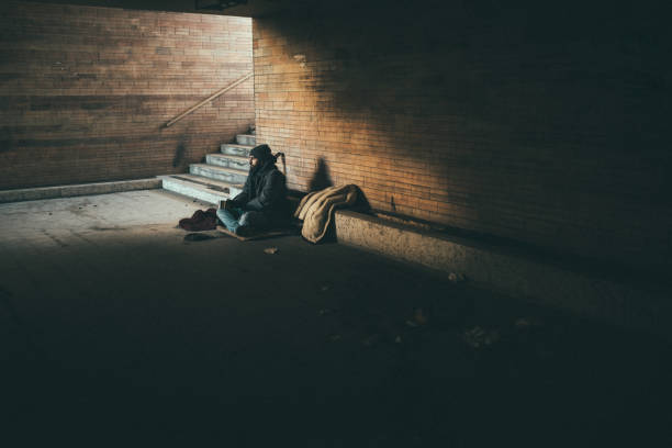 Homeless guy sitting alone One man, young homeless sitting on the street and begging. begging currency beggar poverty stock pictures, royalty-free photos & images