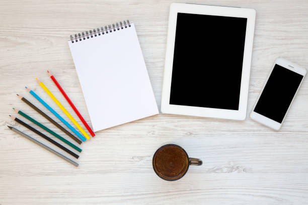 istock Feminine workspace with cup of coffee, smartphone, tablet, notebook, color pencils. Top view. 956176500