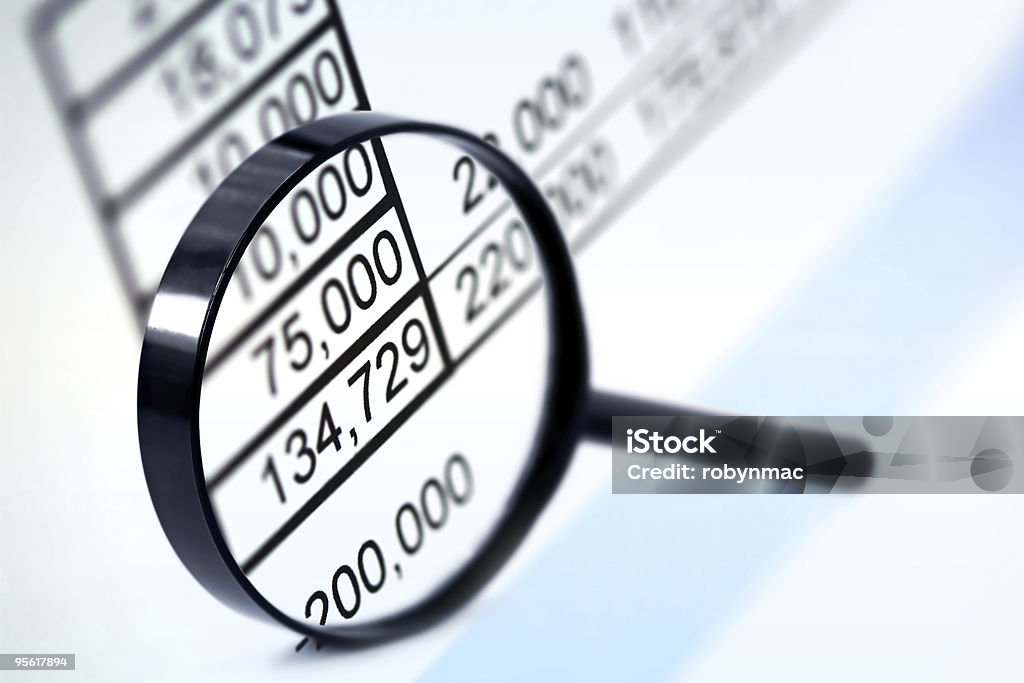 A magnifying lens focusing on the numeric figures Magnifying glass over financial figures.  Very soft focus.  More business concepts: Analyzing Stock Photo