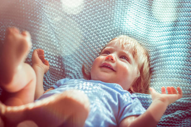 Cute baby boy in bed playing with blanket