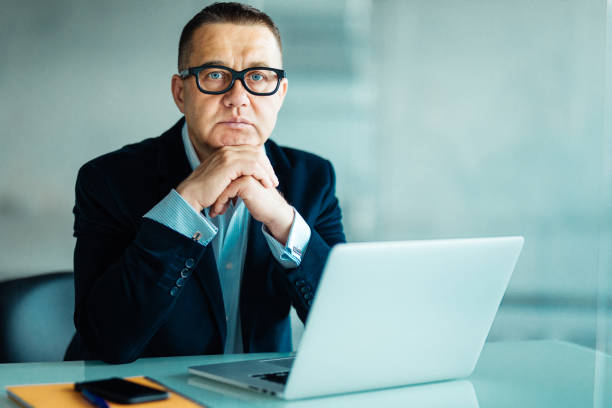 istock Businessman sitting working at laptop computer in a large office 956180176