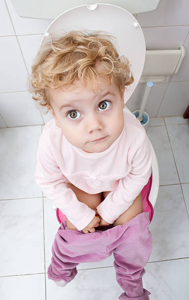 Baby girl sitting on the toilet stock photo