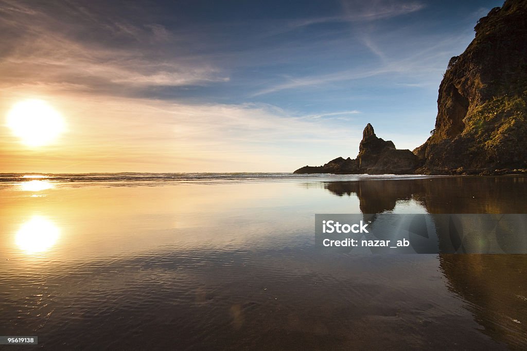 Sunset at Piha beach Piha beach sunset with reflection of lion rock New Zealand Stock Photo