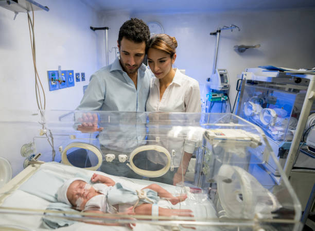istock Man embracing partner at neonatal intensive care unit while both are looking at their newborn son 956193166
