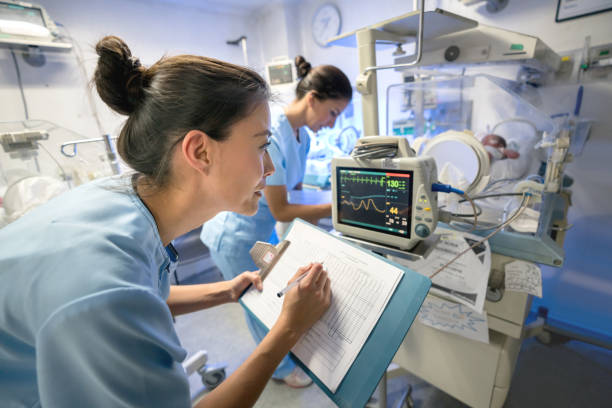 equipe de enfermeiros em unidade de cuidados intensivos neonatal checando sinais vitais de um prematuro e tomar notas, escrever os números em uma área de transferência - delivery room - fotografias e filmes do acervo