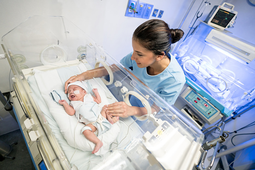 Sweet latin american newborn premature baby in the NICU and sweet nurse trying to calm him