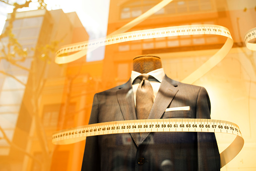Tailor's shop window made to measure tailored suit store mannequin with formal shirt and tie with measuring tape.
