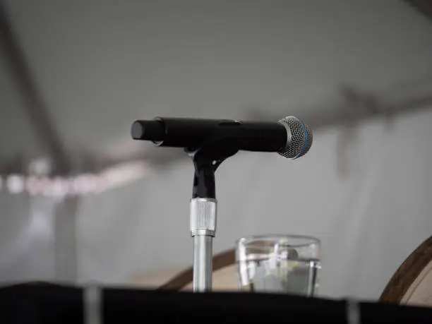 Black microphone sitting on presenter’s table waiting for speaker