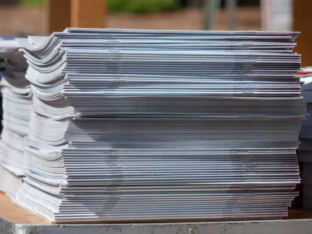 Stack of stapled periodicals sitting in a stack on an outdoors table